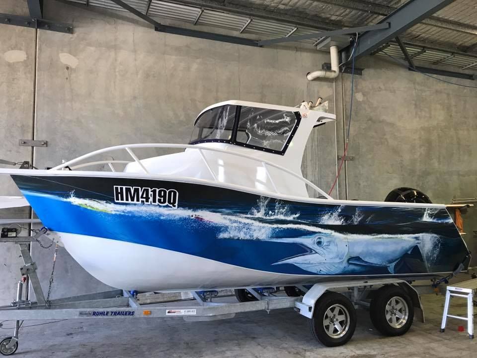 A Boat With a Dolphin on the Side is Parked in a Garage — Currumbin Trimmers In Murwillumbah, NSW