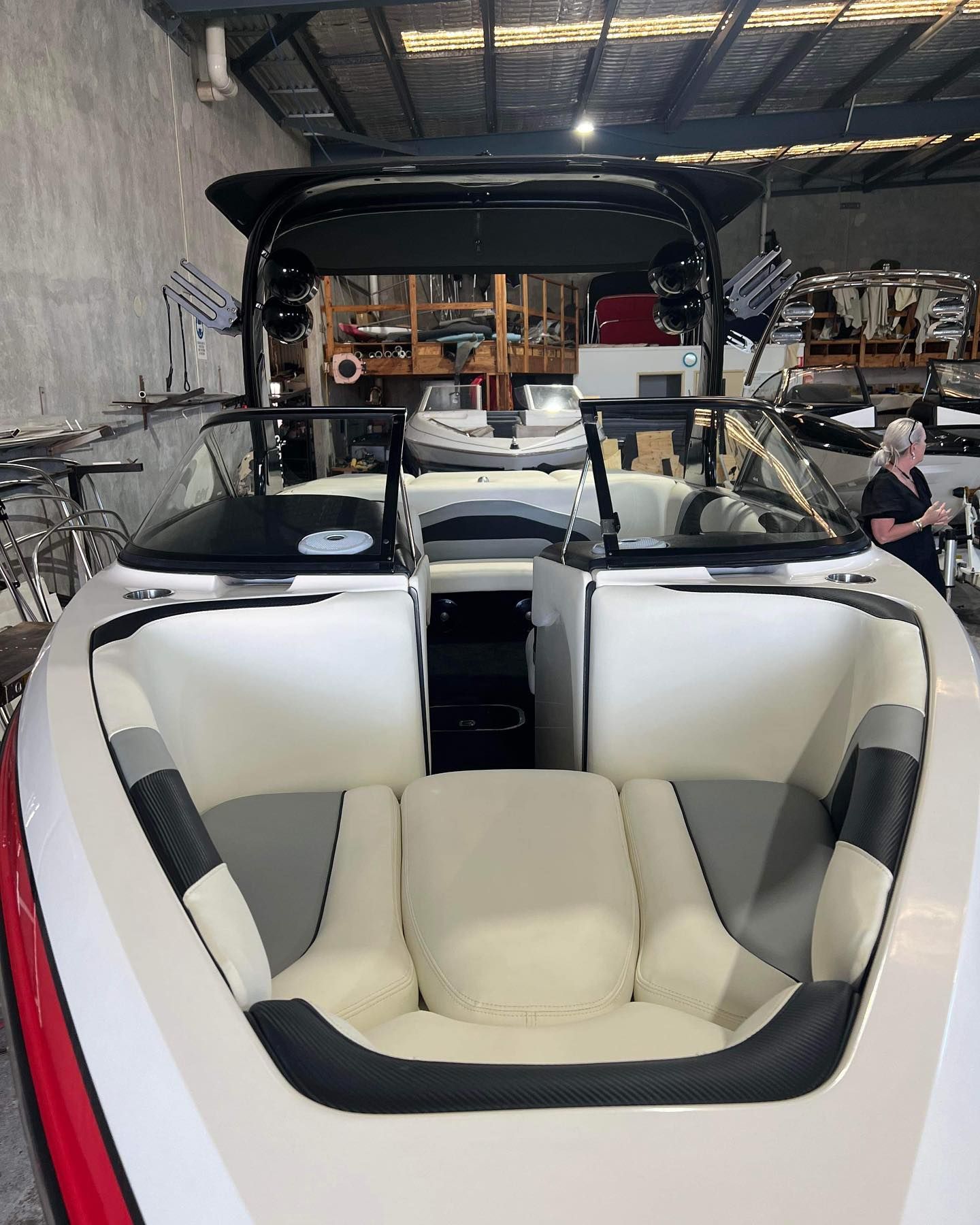 A Boat is Sitting in a Warehouse With a Woman Standing Next to It — Currumbin Trimmers In Currumbin Waters, QLD