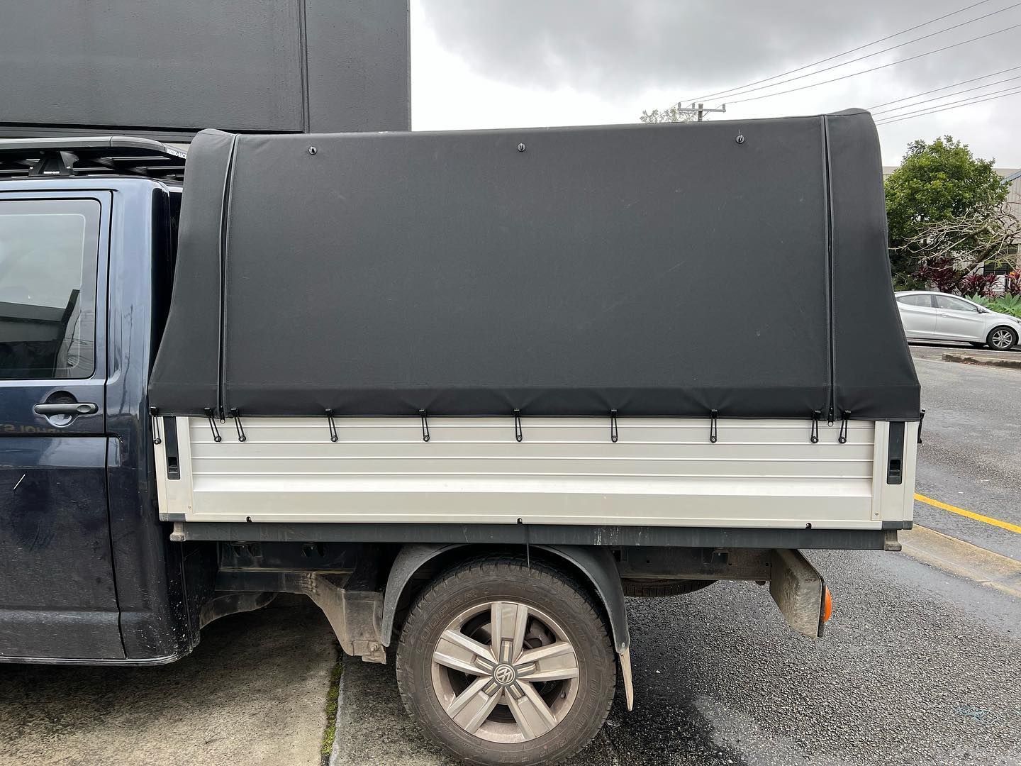 A Black Truck With a Black Canopy is Parked on the Side of the Road — Currumbin Trimmers In Byron Bay, NSW