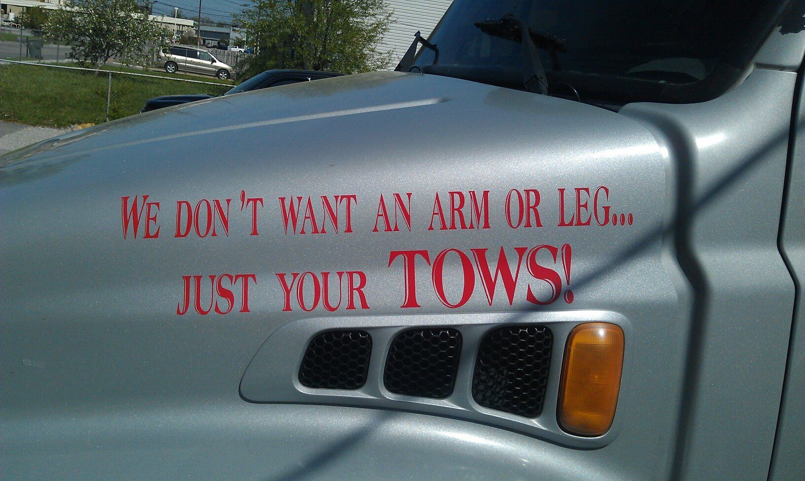 A silver truck has a sticker on the hood that says 