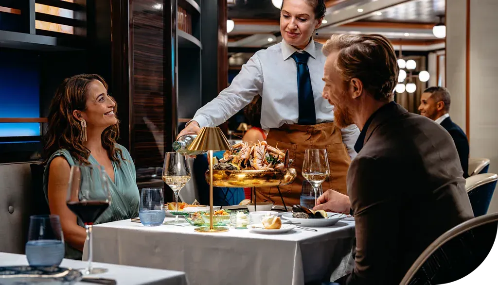 Couple dining, served wine by a waiter in an upscale restaurant.