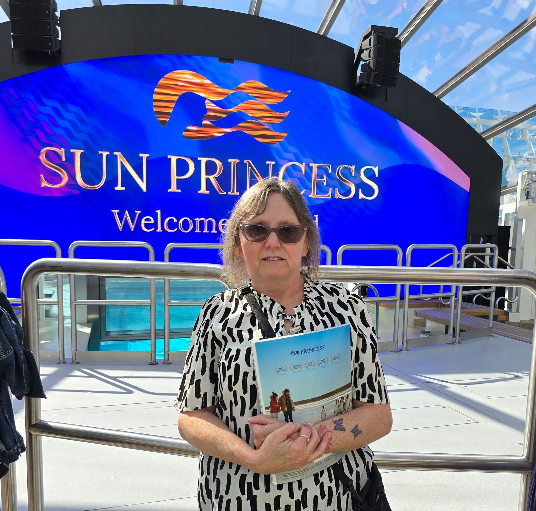 A woman stands in front of a sign that says sun princess