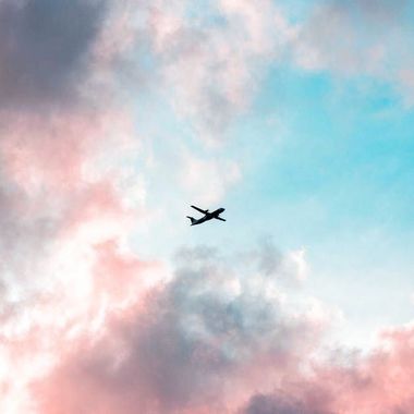 A small airplane is flying through a cloudy sky.