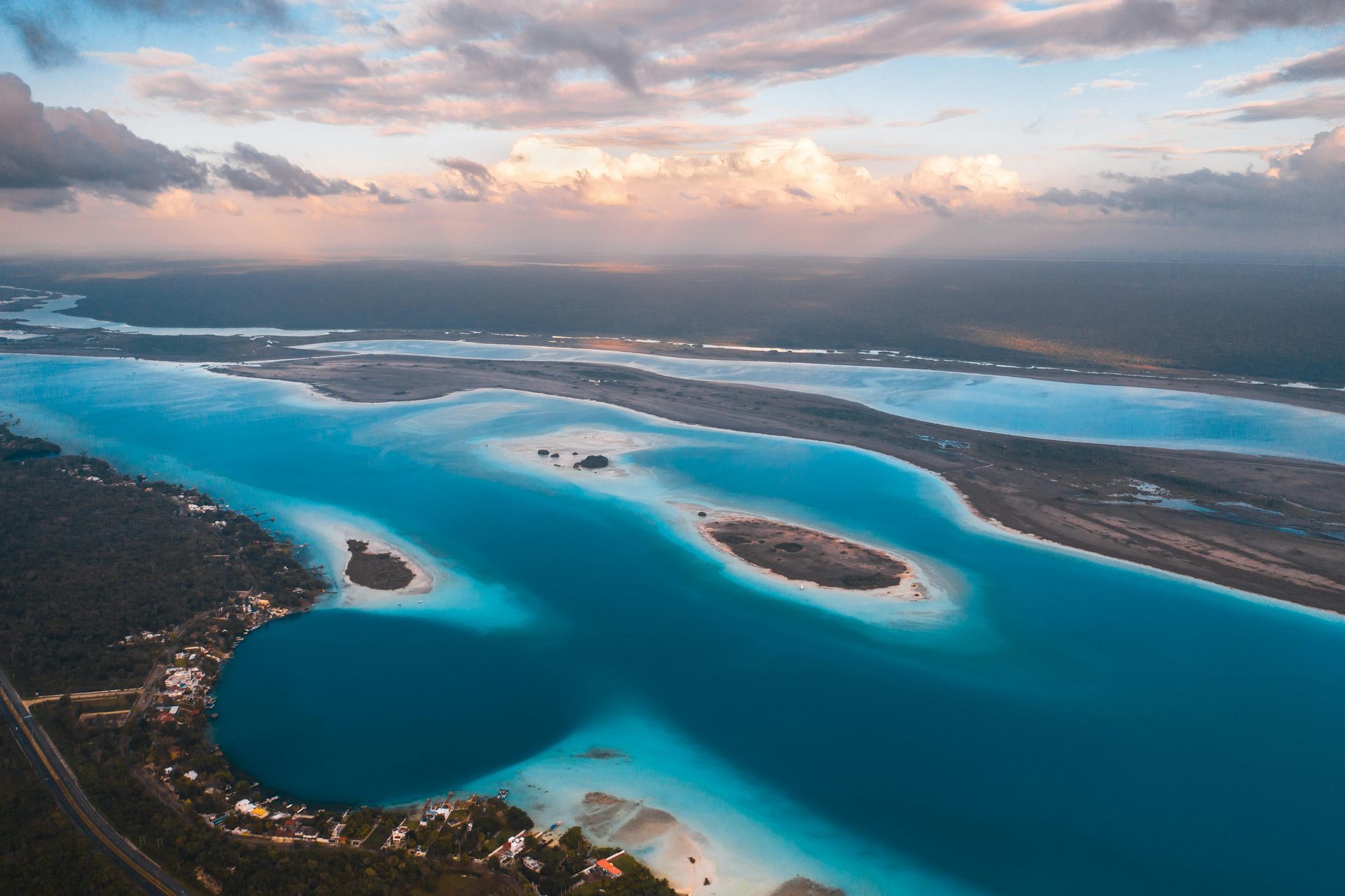Aerial view of the Lagoon of Bacalar in Mexico, with turquoise water, islands, and a cloudy sky.