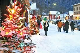 People watch fireworks over an outdoor ice rink at night, surrounded by buildings with lit windows.