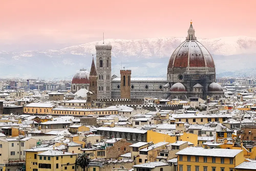 Hand in a mitten holding candy canes shaped into a heart, with a festive arch in the background.