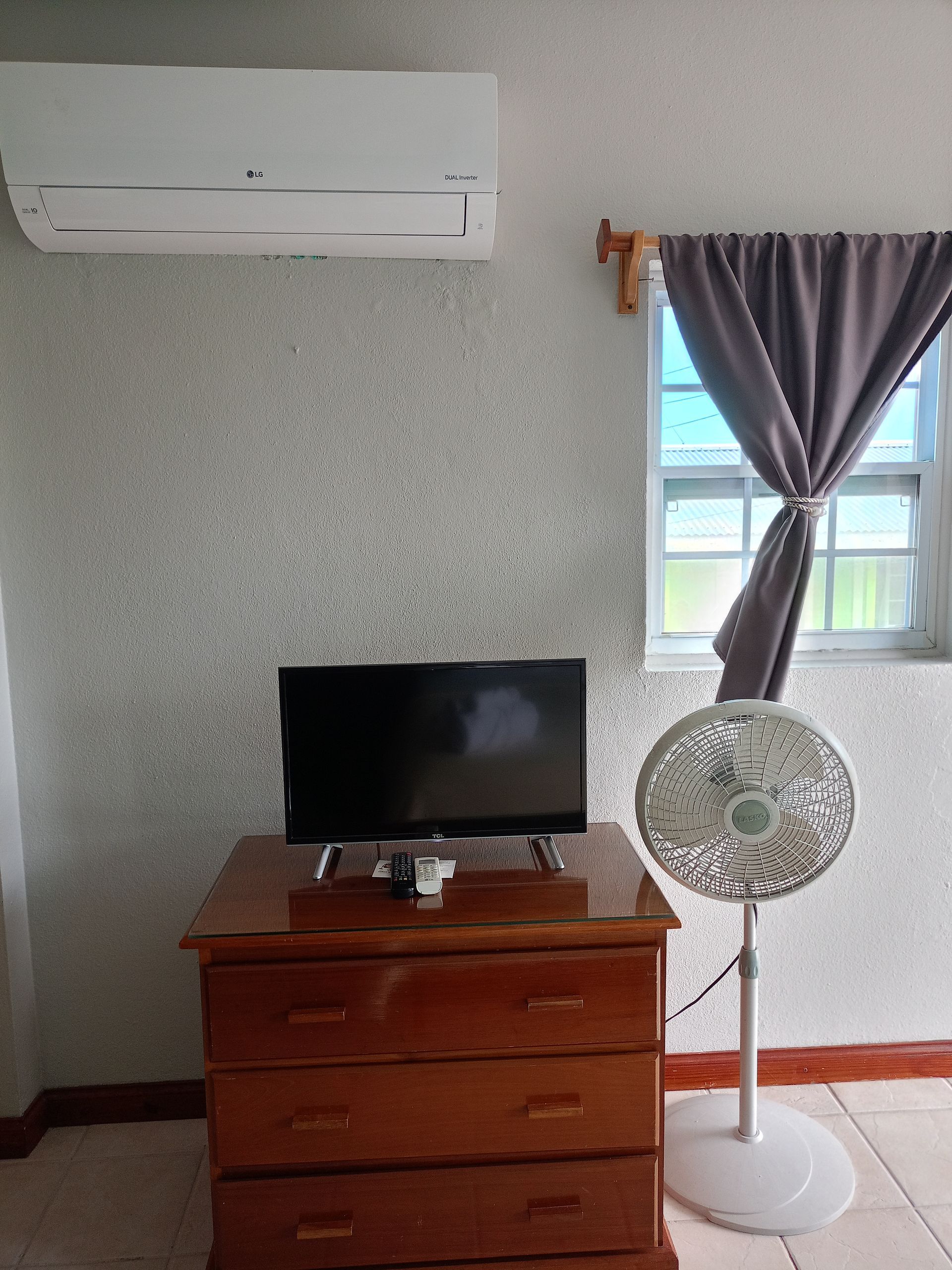 Bedroom with double bed, window with ocean view, brown curtains, and a nightstand with a lamp.