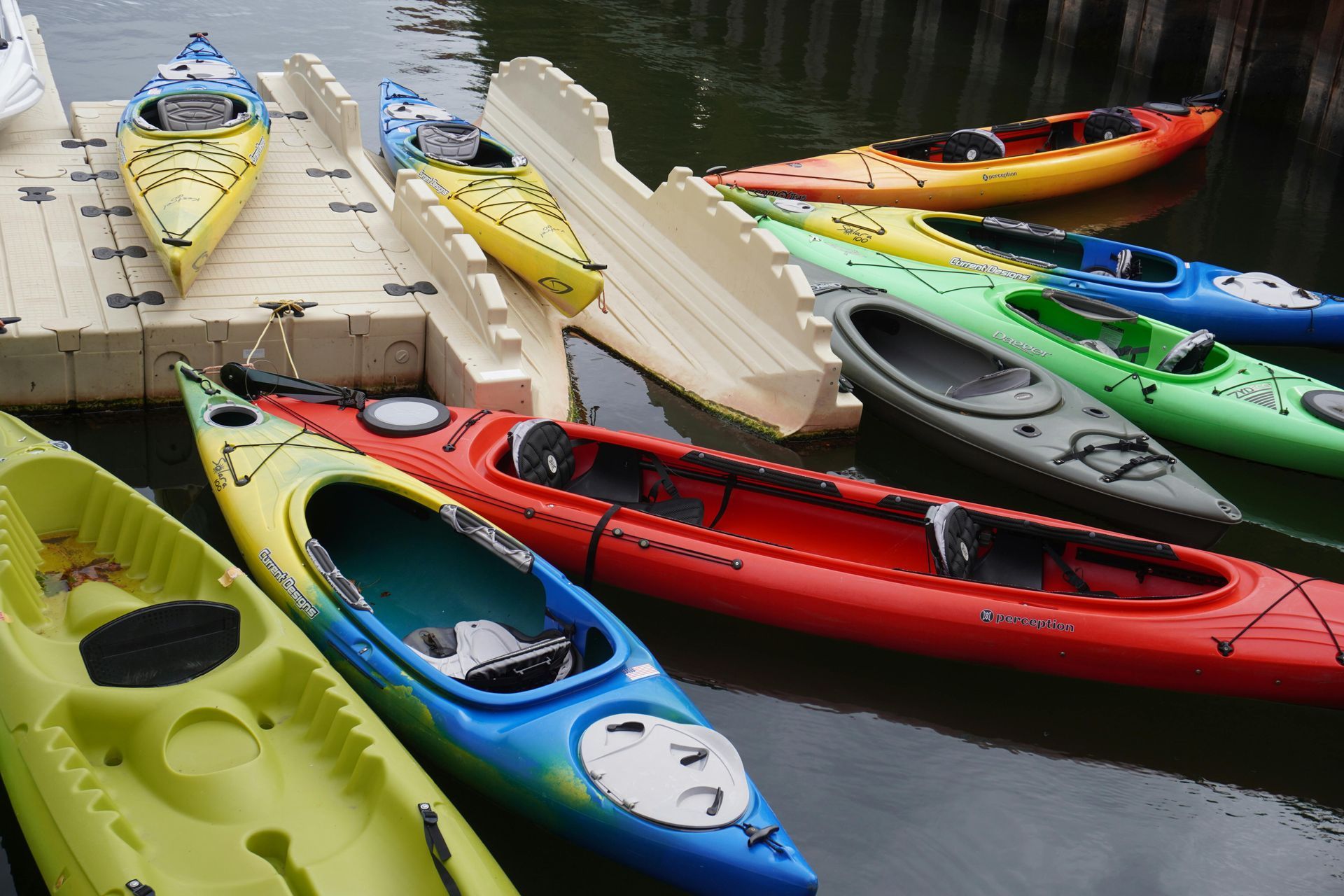 Colorful kayaks docked at a harbor, some on a ramp.