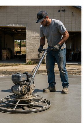 Construction worker using power trowel to finish a concrete pad in front of a house in Cornwall, ON