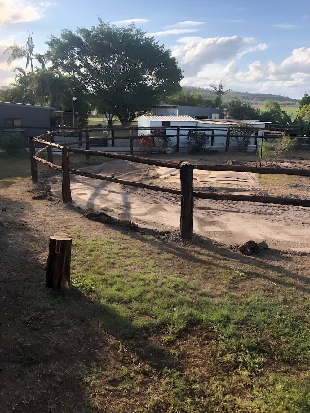 A Wooden Fence Surrounds A Dirt Field With A House In The Background — D.T. Fencing In Bakers Creek, QLD