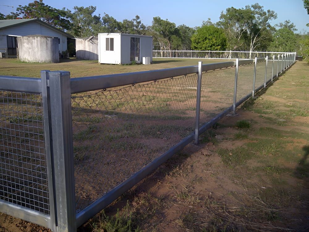 A Metal Fence Surrounds A Grassy Field With A House In The Background — D.T. Fencing In Bakers Creek, QLD