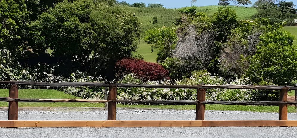 A Wooden Fence Surrounds A Gravel Road With Trees In The Background — D.T. Fencing In Bakers Creek, QLD