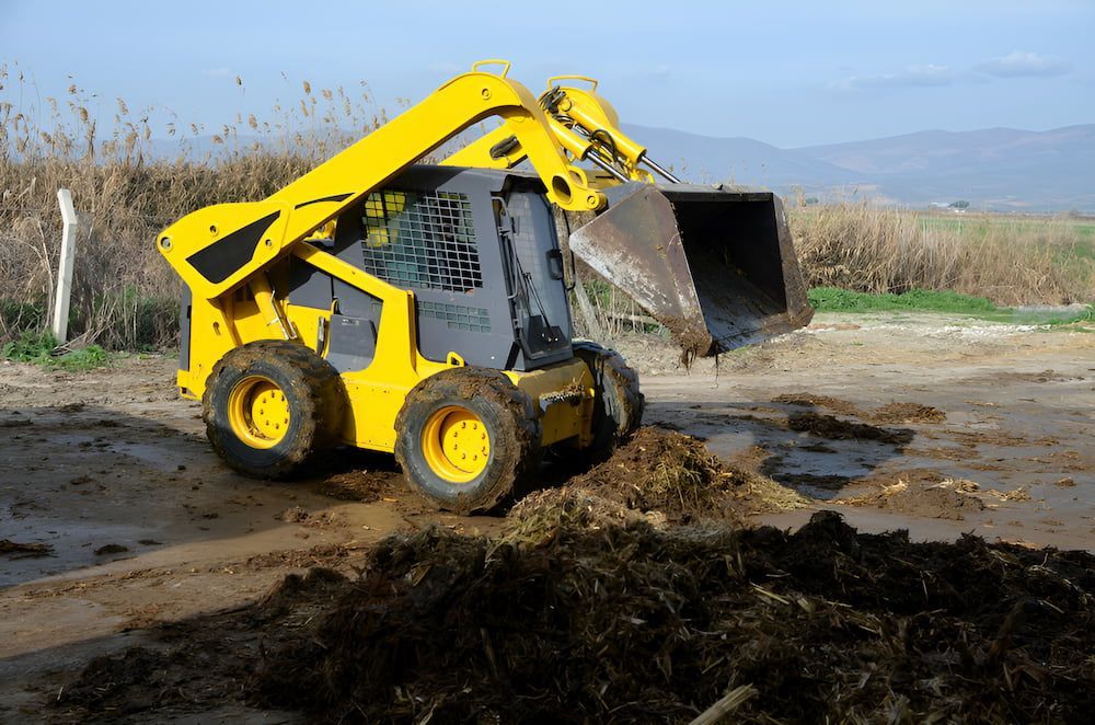 A Yellow Tractor Is Digging A Hole In The Dirt — D.T. Fencing In Bakers Creek, QLD