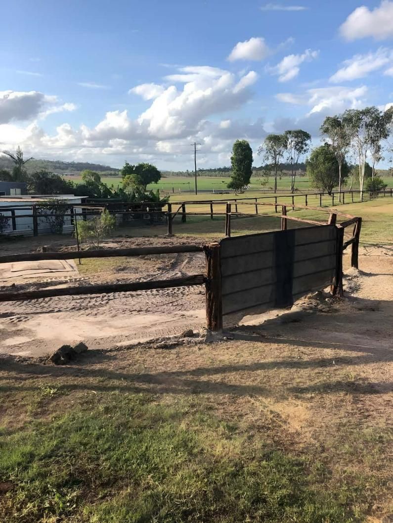 A Wooden Fence Surrounds A Dirt Field With Trees In The Background — D.T. Fencing In Bakers Creek, QLD