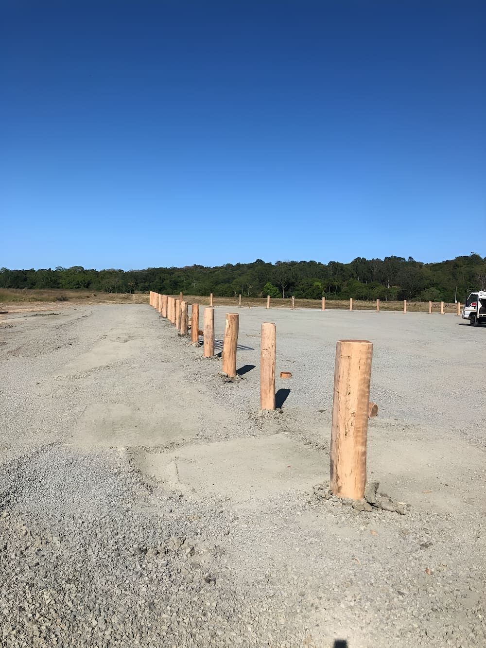 A Row Of Wooden Poles Are Lined Up In A Gravel Parking Lot — D.T. Fencing In Bakers Creek, QLD