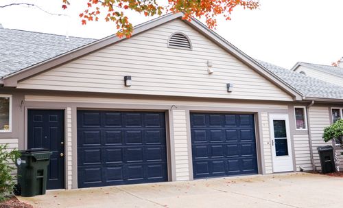 Suburban house exterior with three dark blue garage doors and a white front entrance