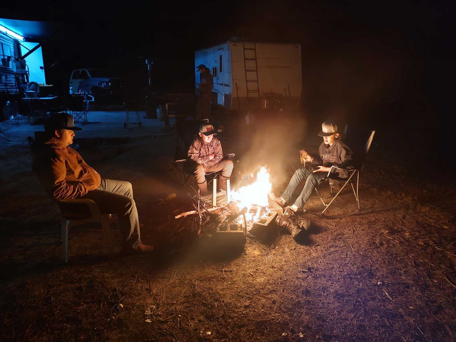 people are sitting around a campfire 