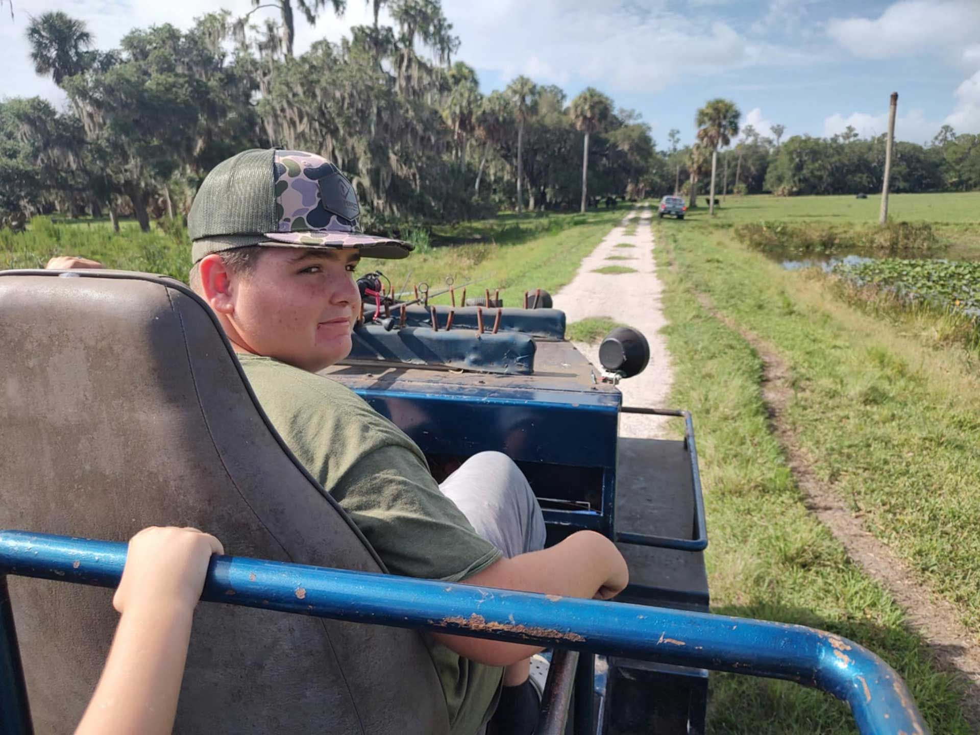boy is sitting in vehicle on a dirt road