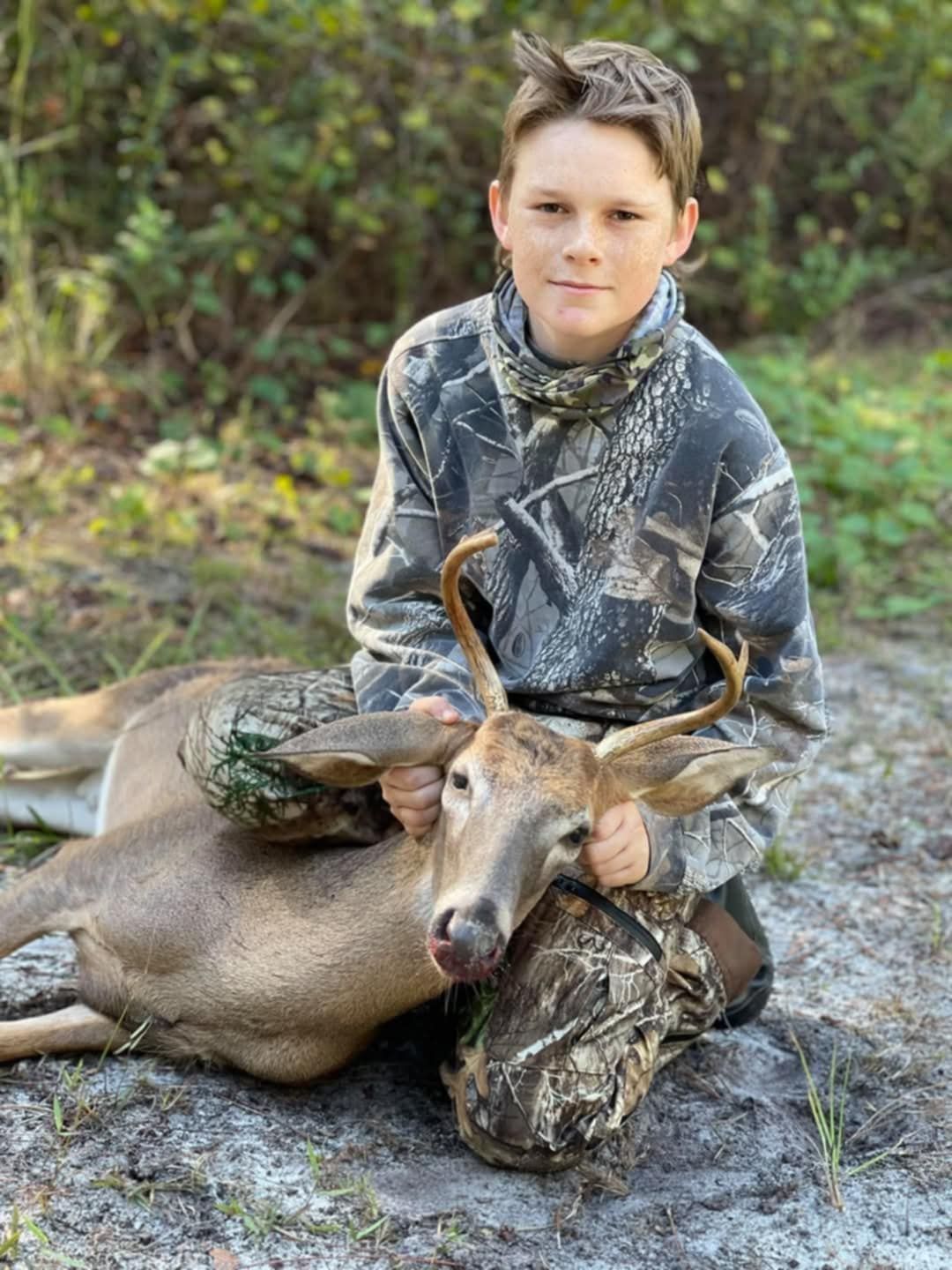 Boy holding up a deer he shot