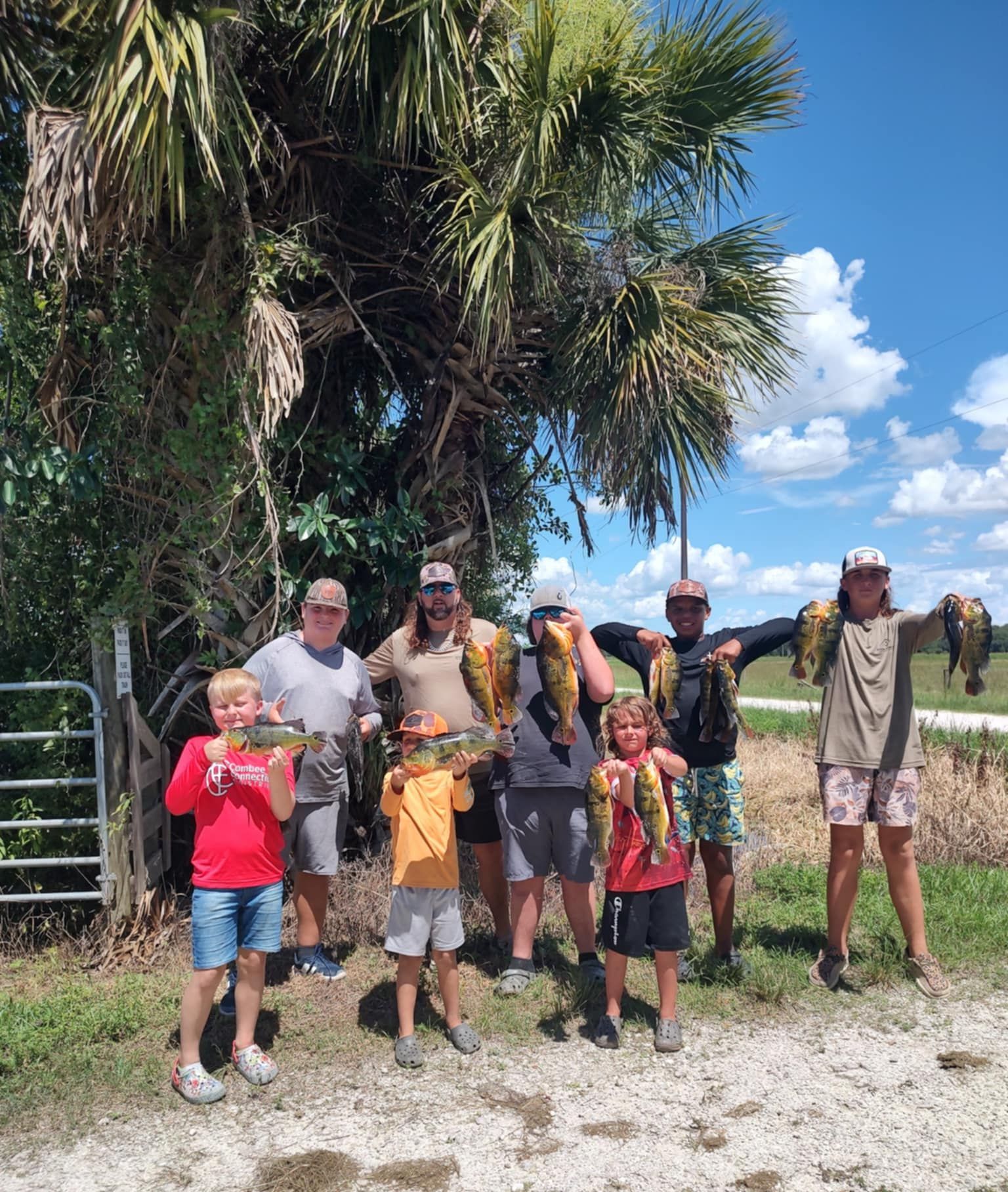 Boys outside in a group with counselors showing off fish they caught