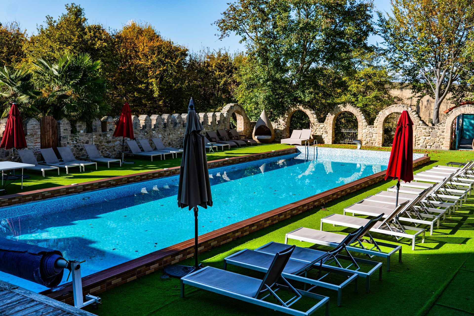 A large swimming pool surrounded by chairs and umbrellas.