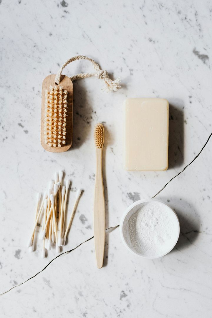 A toothbrush , soap , cotton swabs , and a bowl of baking soda are on a table.