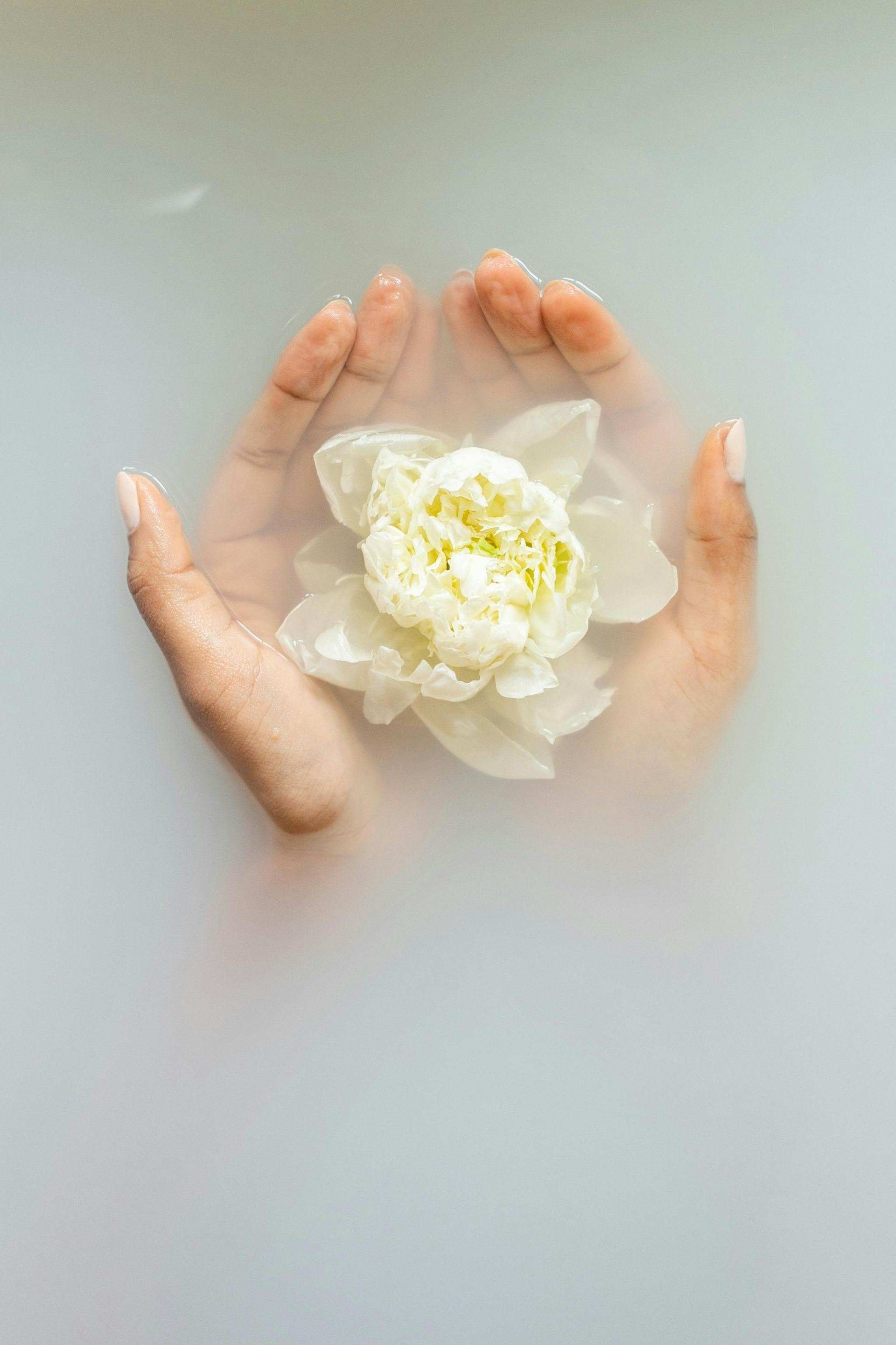 A woman is taking a bath and holding a white flower in her hands.