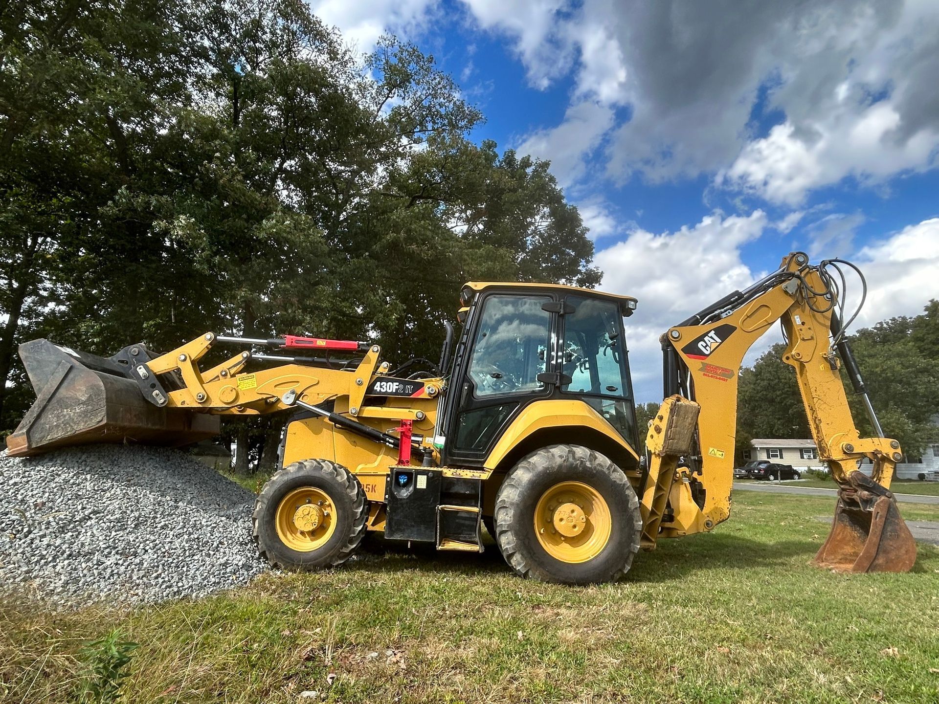 A yellow backhoe is sitting in a grassy field.