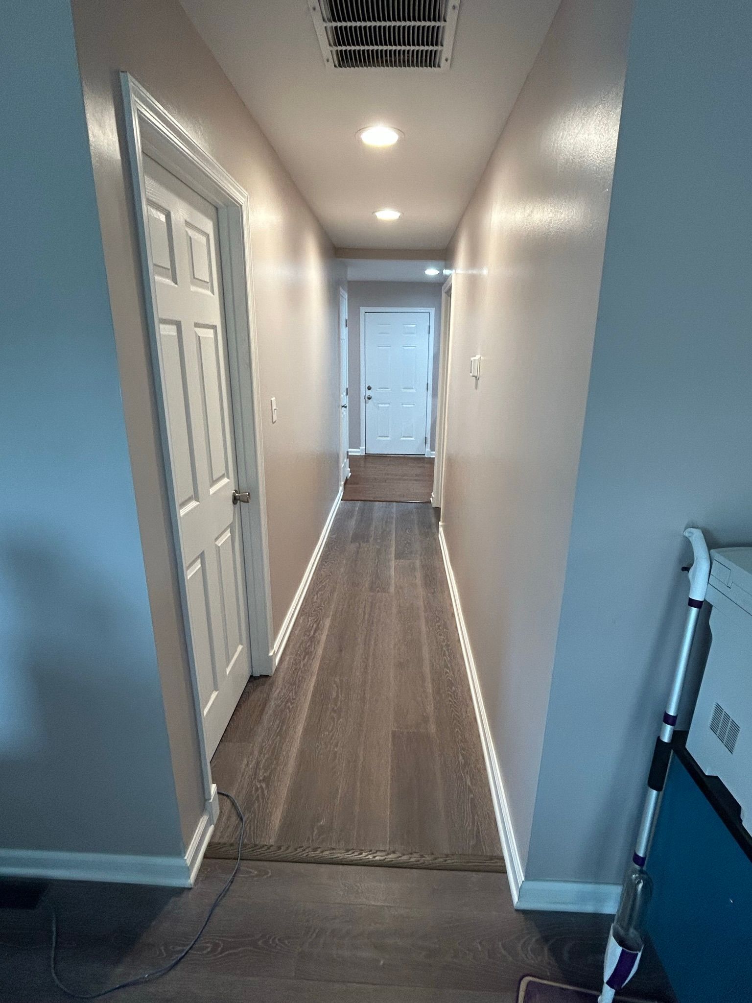 A long hallway in a house with a vacuum cleaner on the floor.