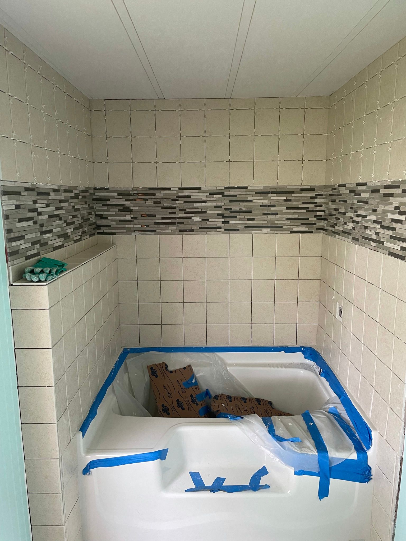 A bathtub is taped to the wall in a bathroom.