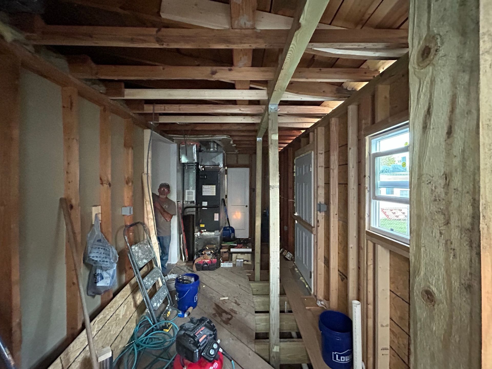 A man is standing in a hallway of a house under construction.