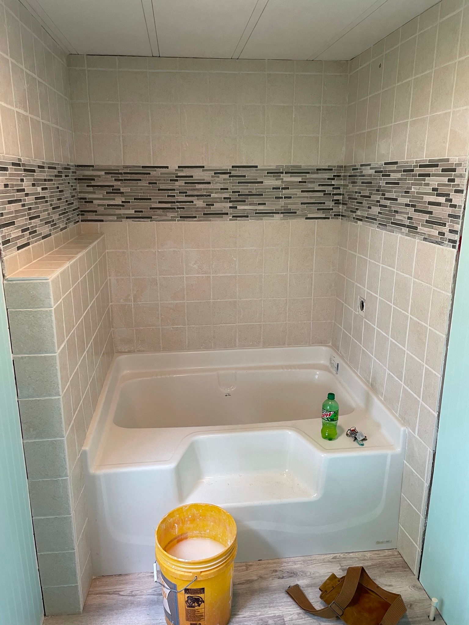 A bathroom with a bathtub and a bucket of soap on the floor.