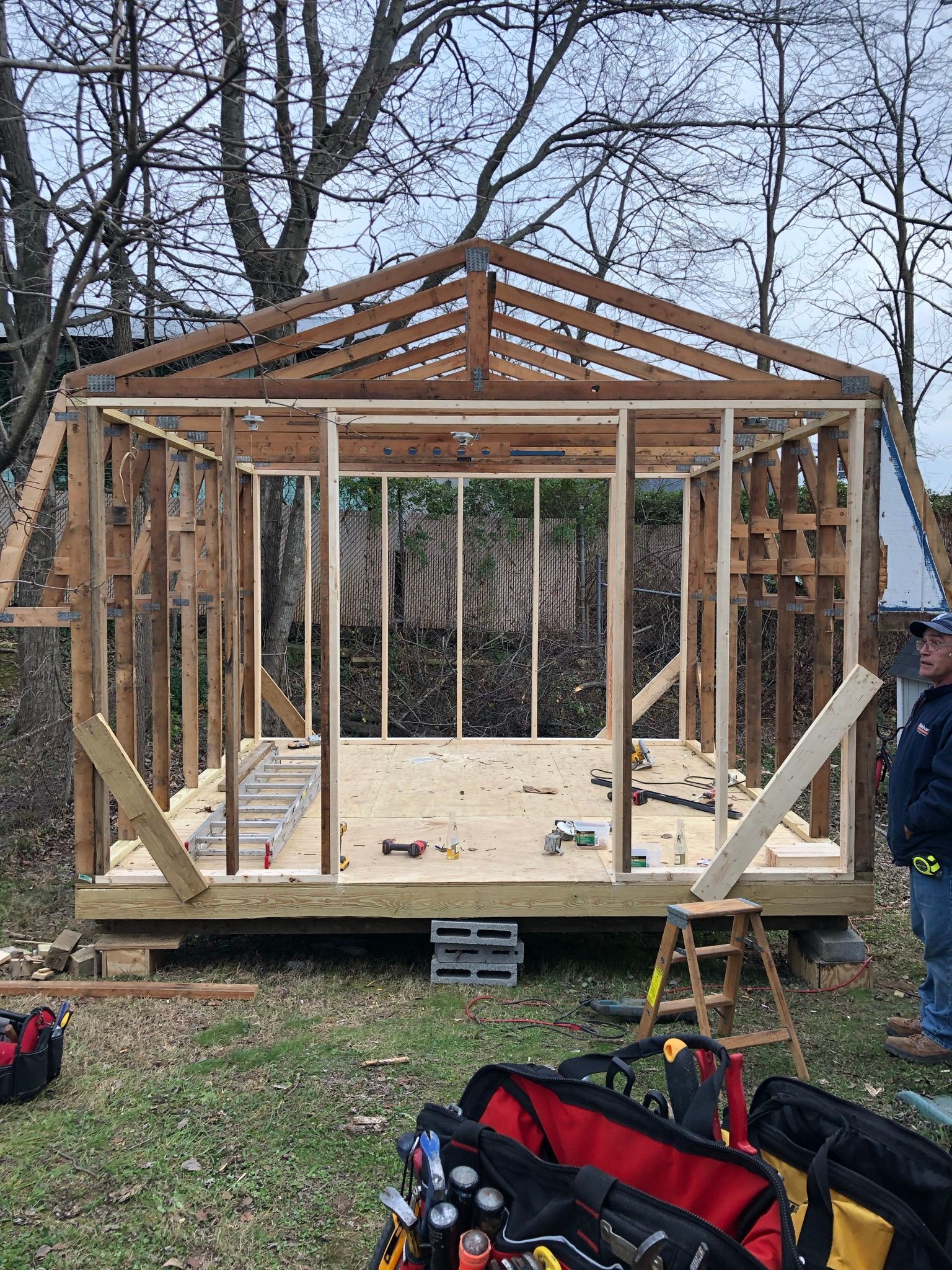 A man is standing in front of a wooden structure under construction.