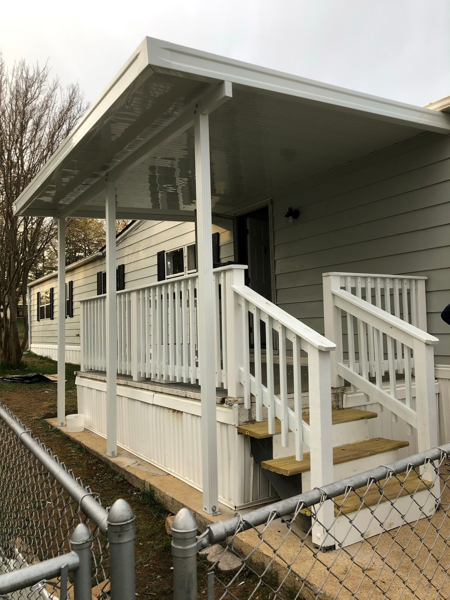 A white mobile home with a covered porch and stairs.
