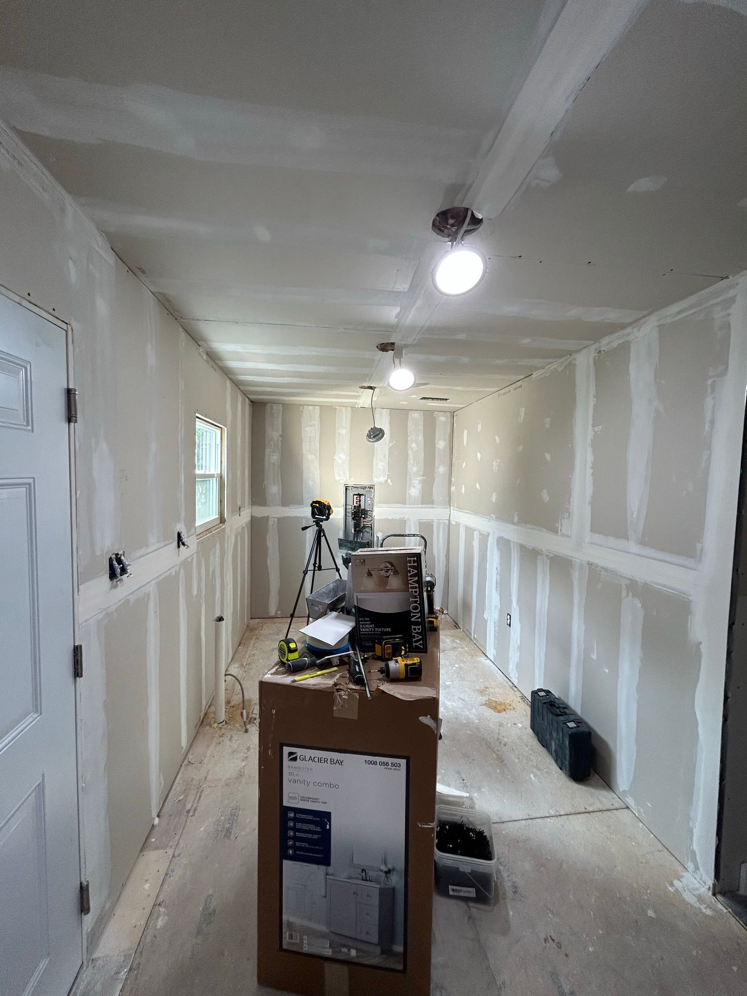 A long hallway with drywall walls and a box on the floor.
