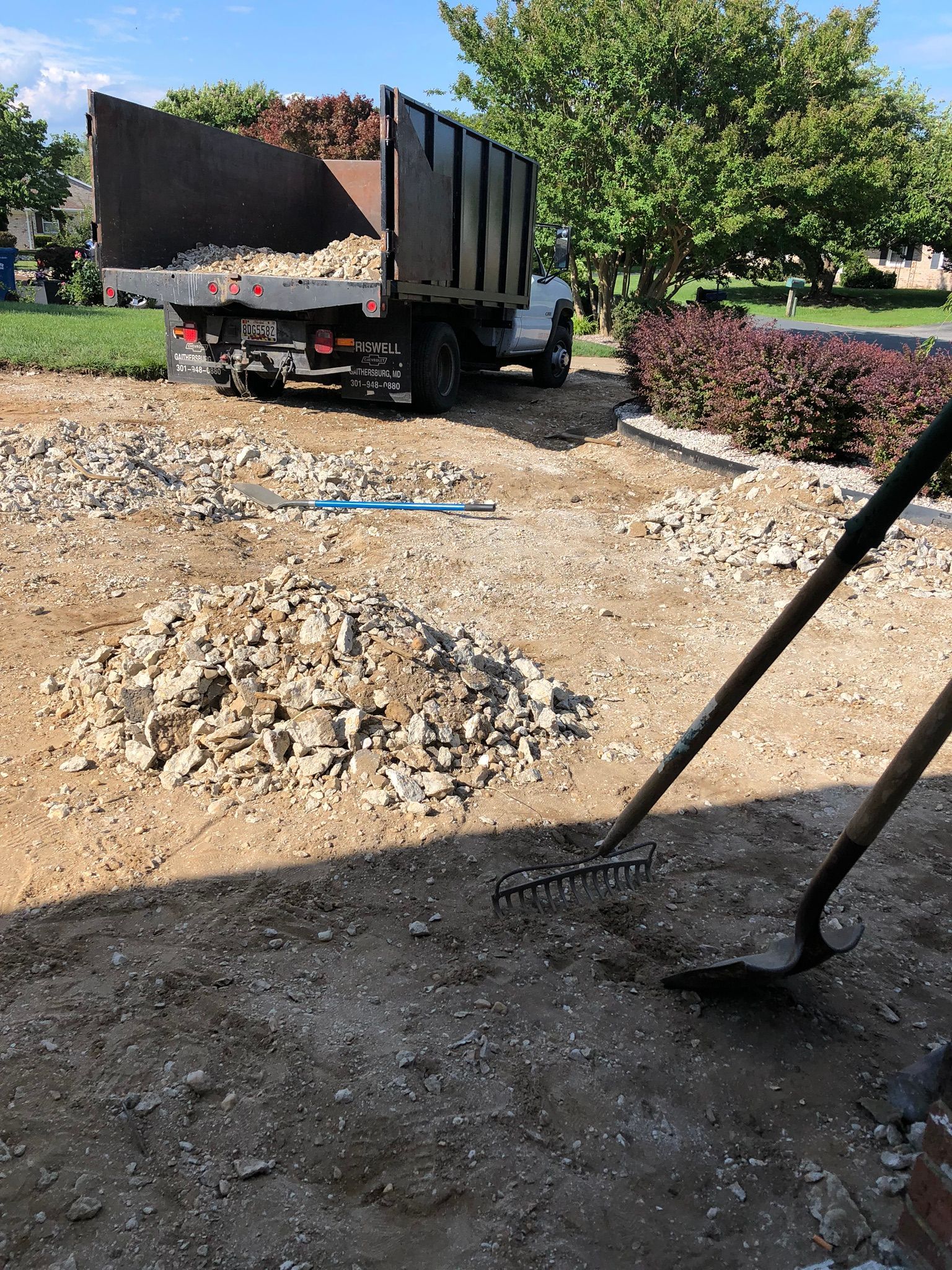 A person is raking dirt in front of a dump truck.