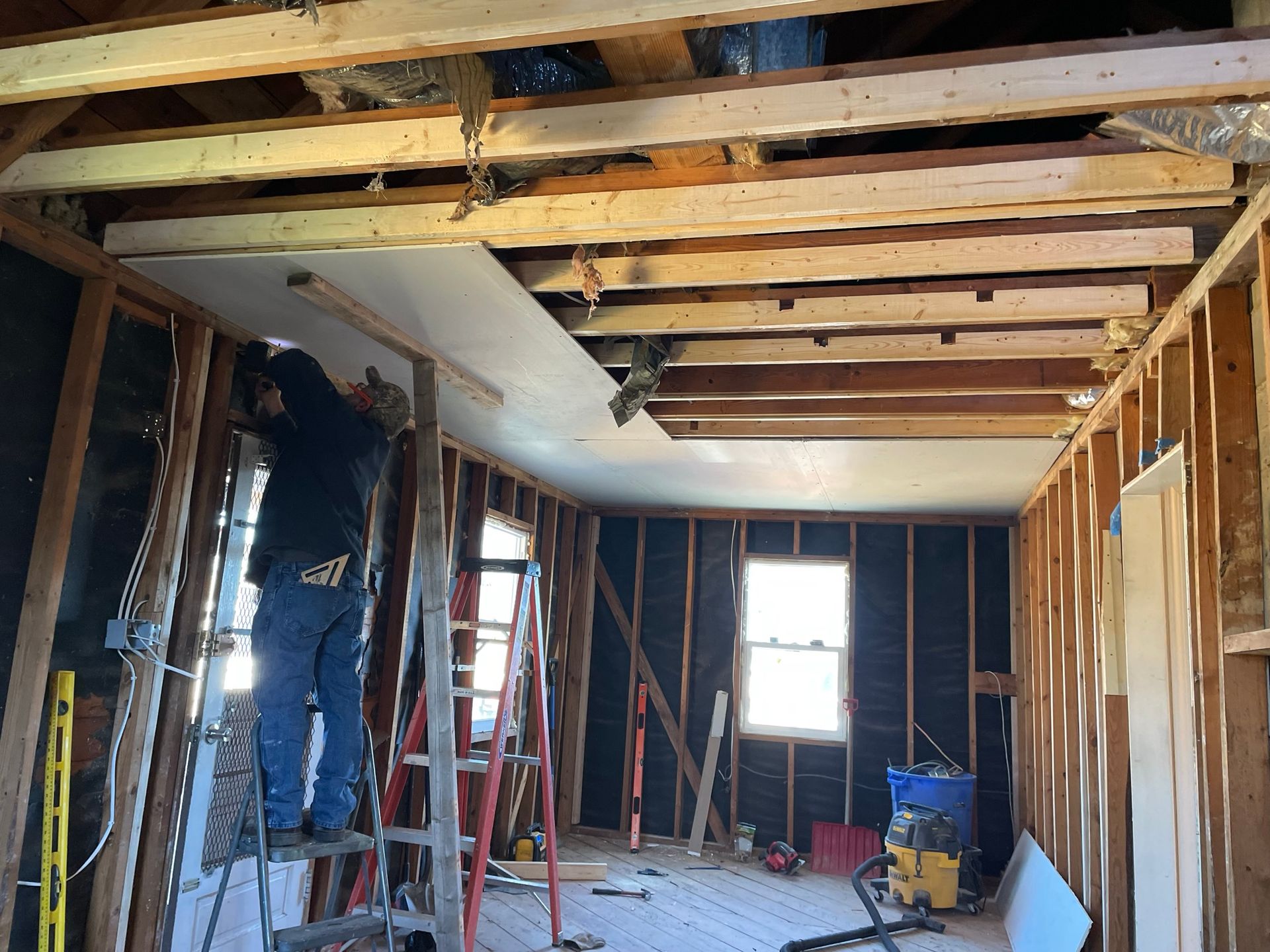 A man is working on the ceiling of a house.
