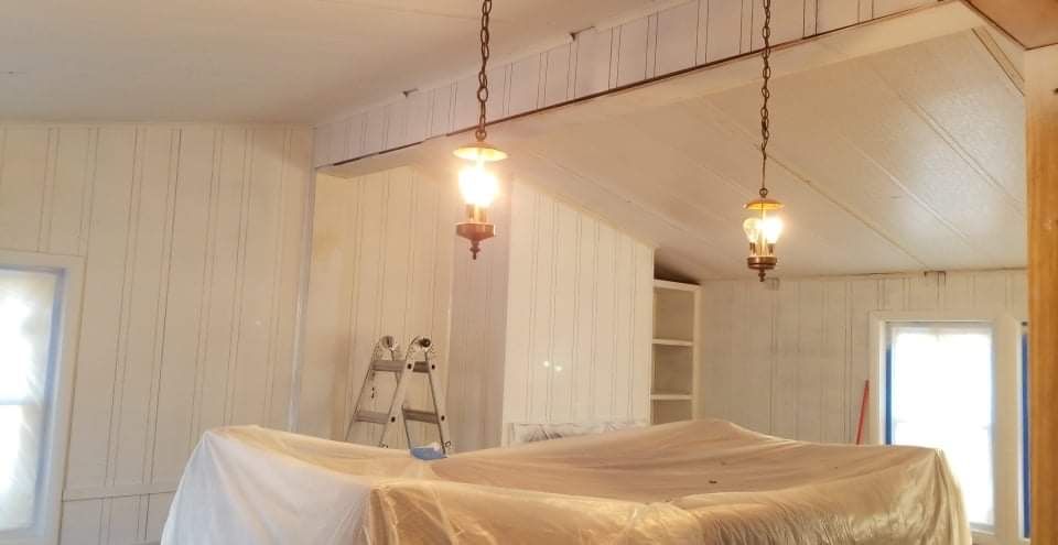 A room with a ladder and lamps hanging from the ceiling.