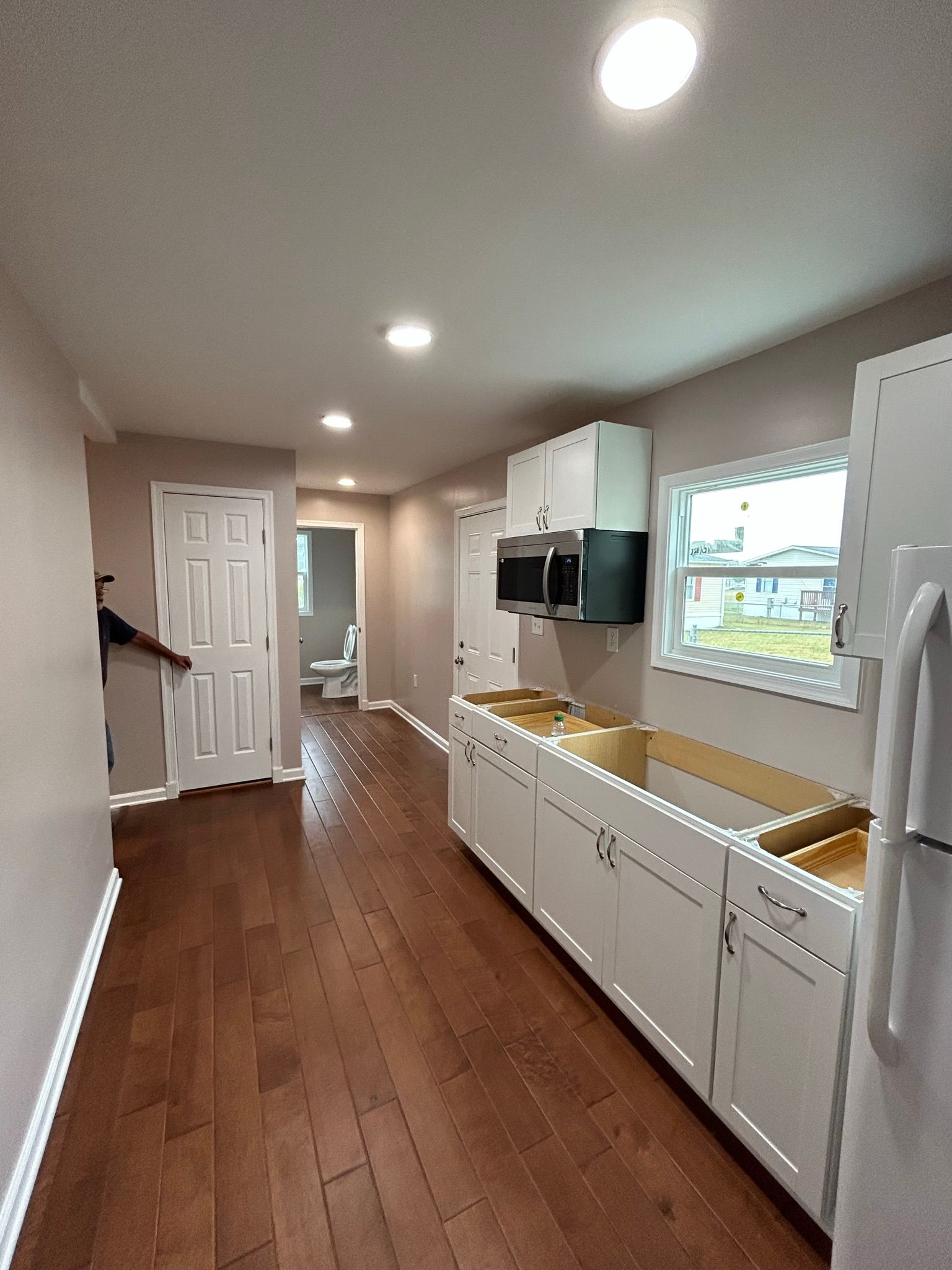 A kitchen with white cabinets , a sink , a microwave , and a refrigerator.