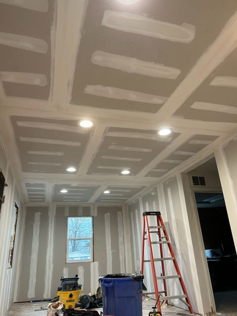 A room with a ladder and a vacuum cleaner in it is being remodeled.