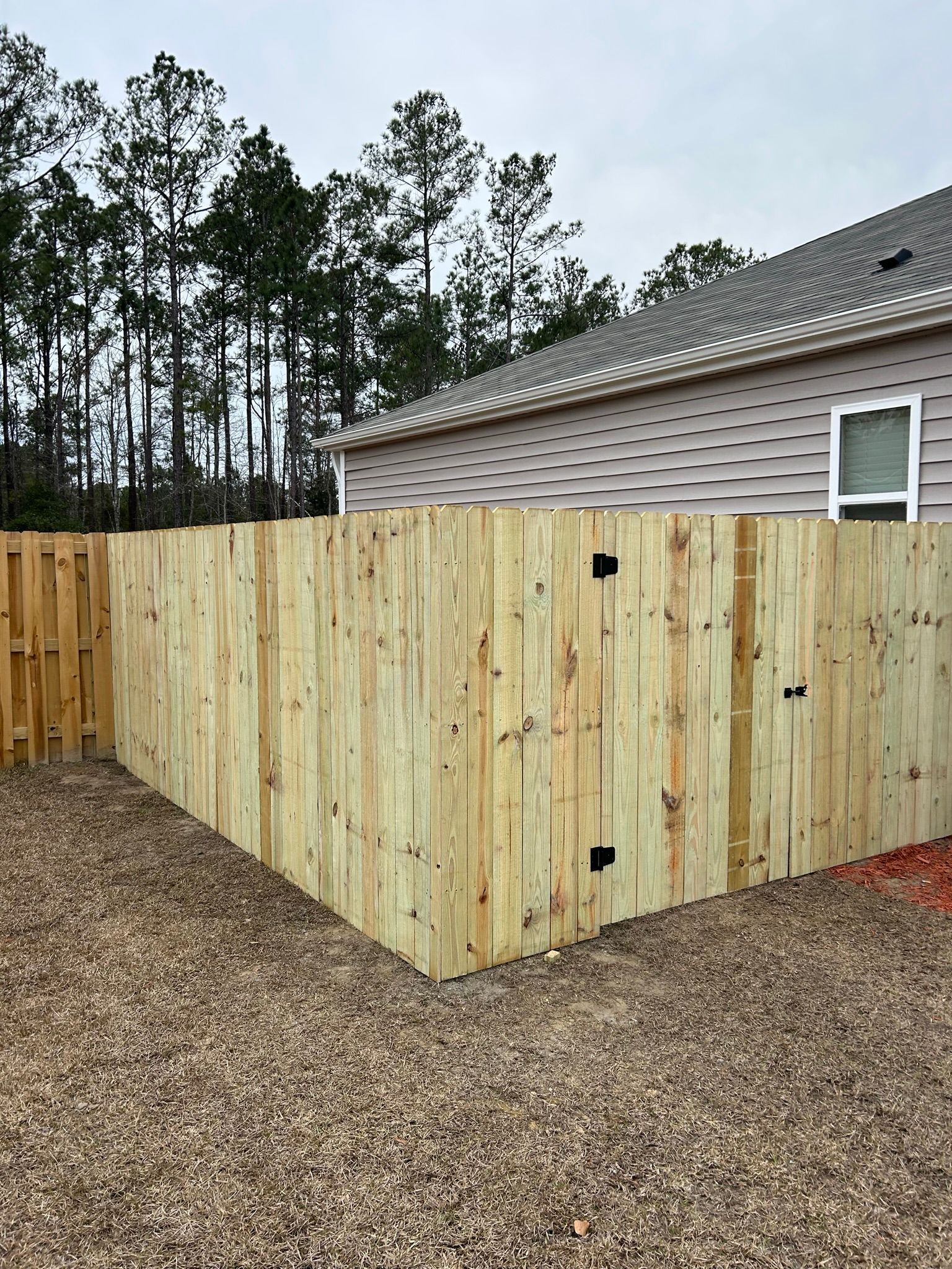 A wooden fence is sitting in front of a house.