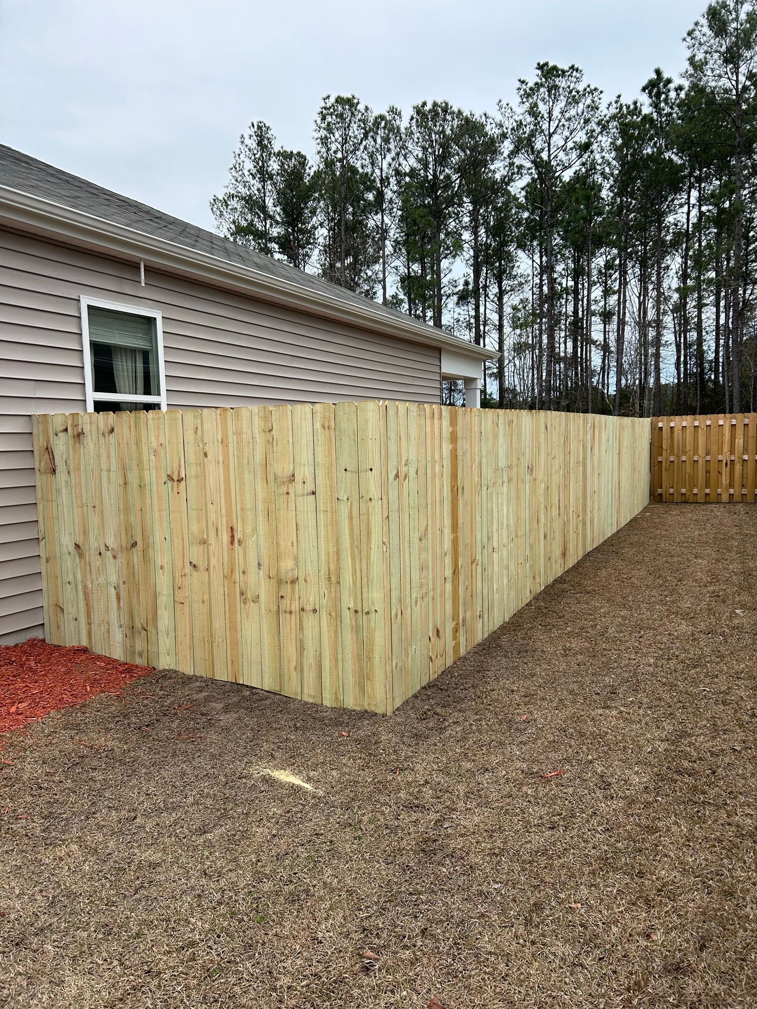 A wooden fence is in the backyard of a house.