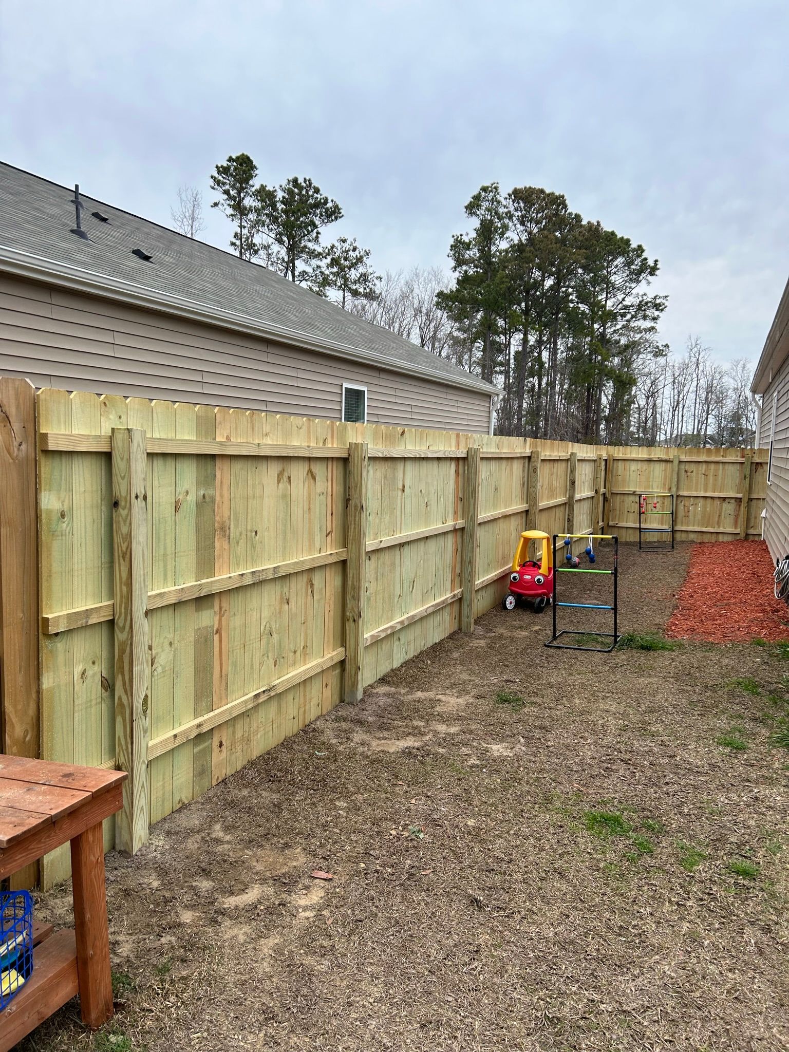 A wooden fence is being built in the backyard of a house.