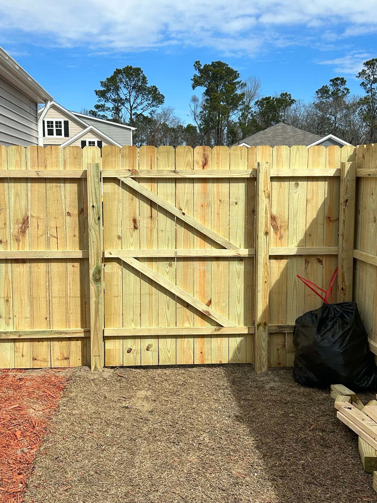 A wooden fence with a gate in the backyard of a house.