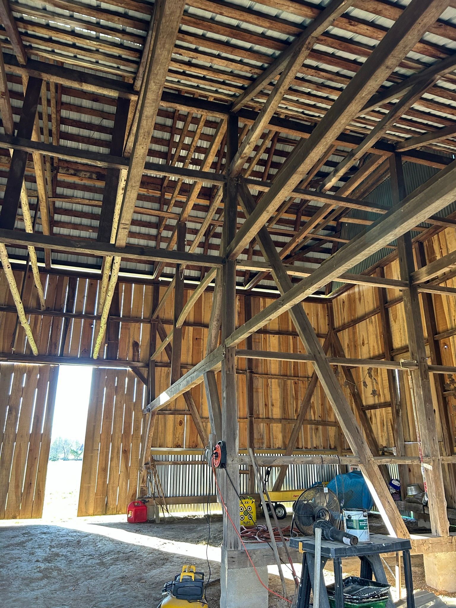 The inside of a wooden barn with a metal roof.