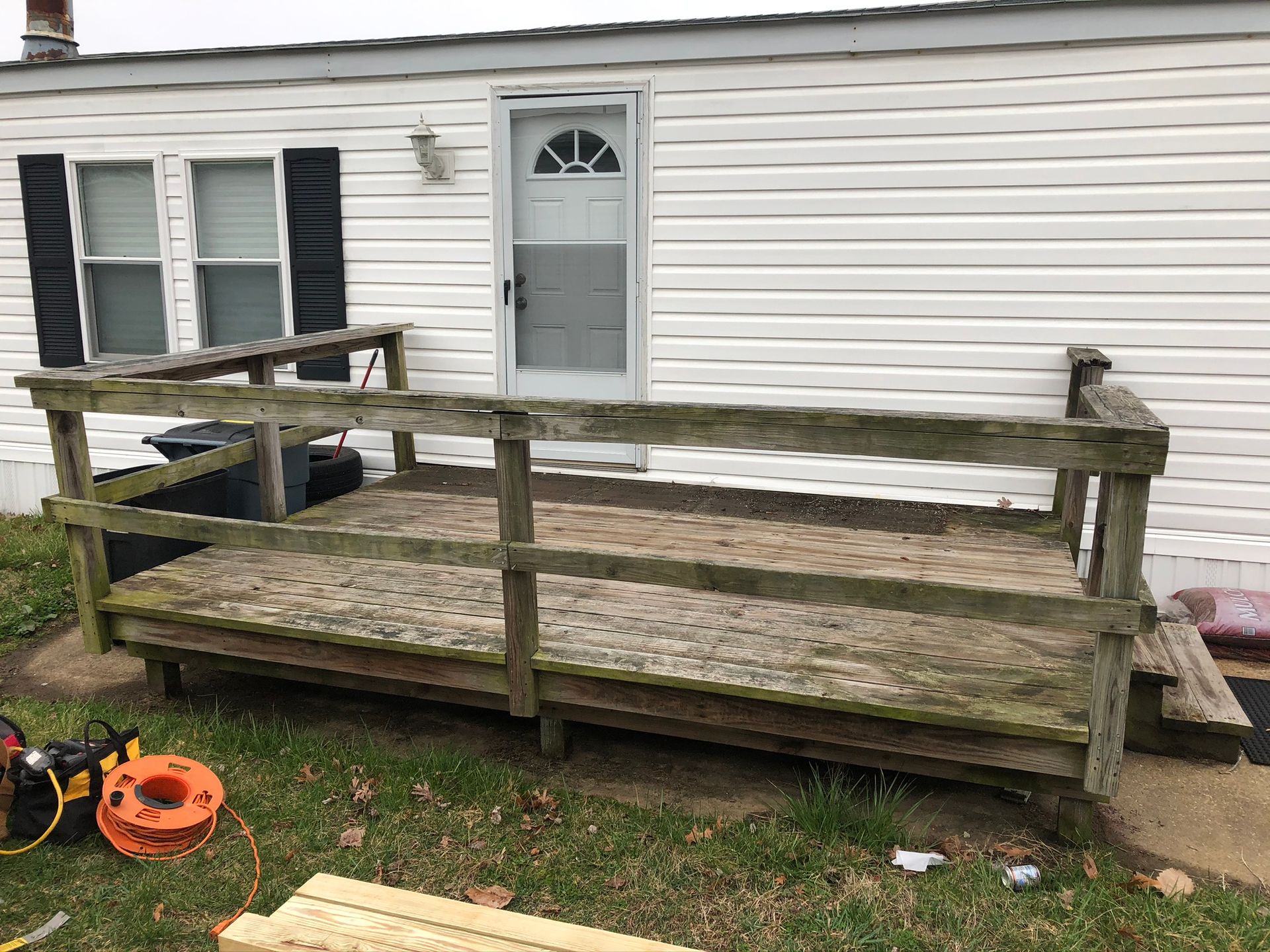 A mobile home with a wooden deck in front of it.