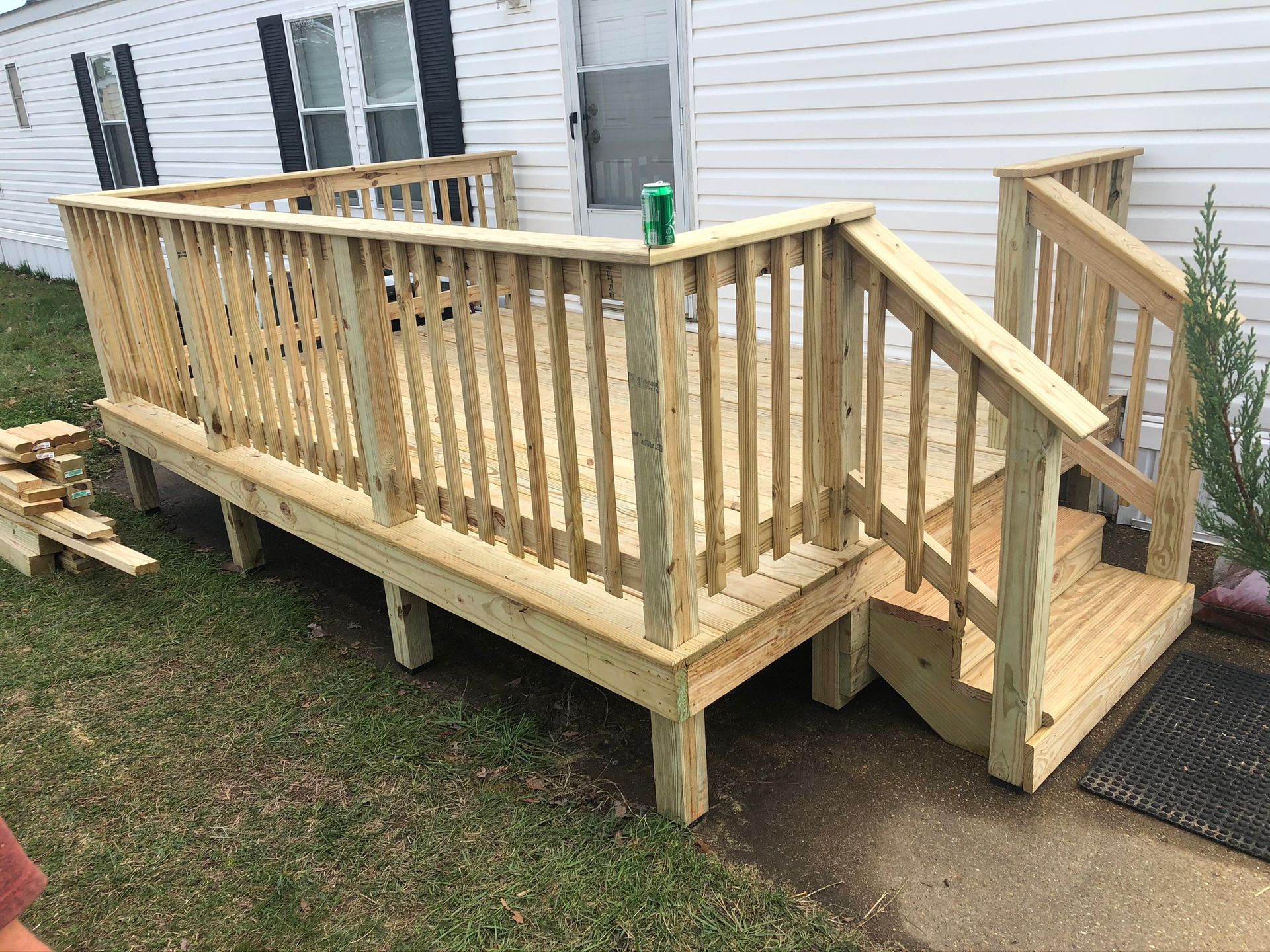 A wooden deck with stairs is in front of a mobile home.