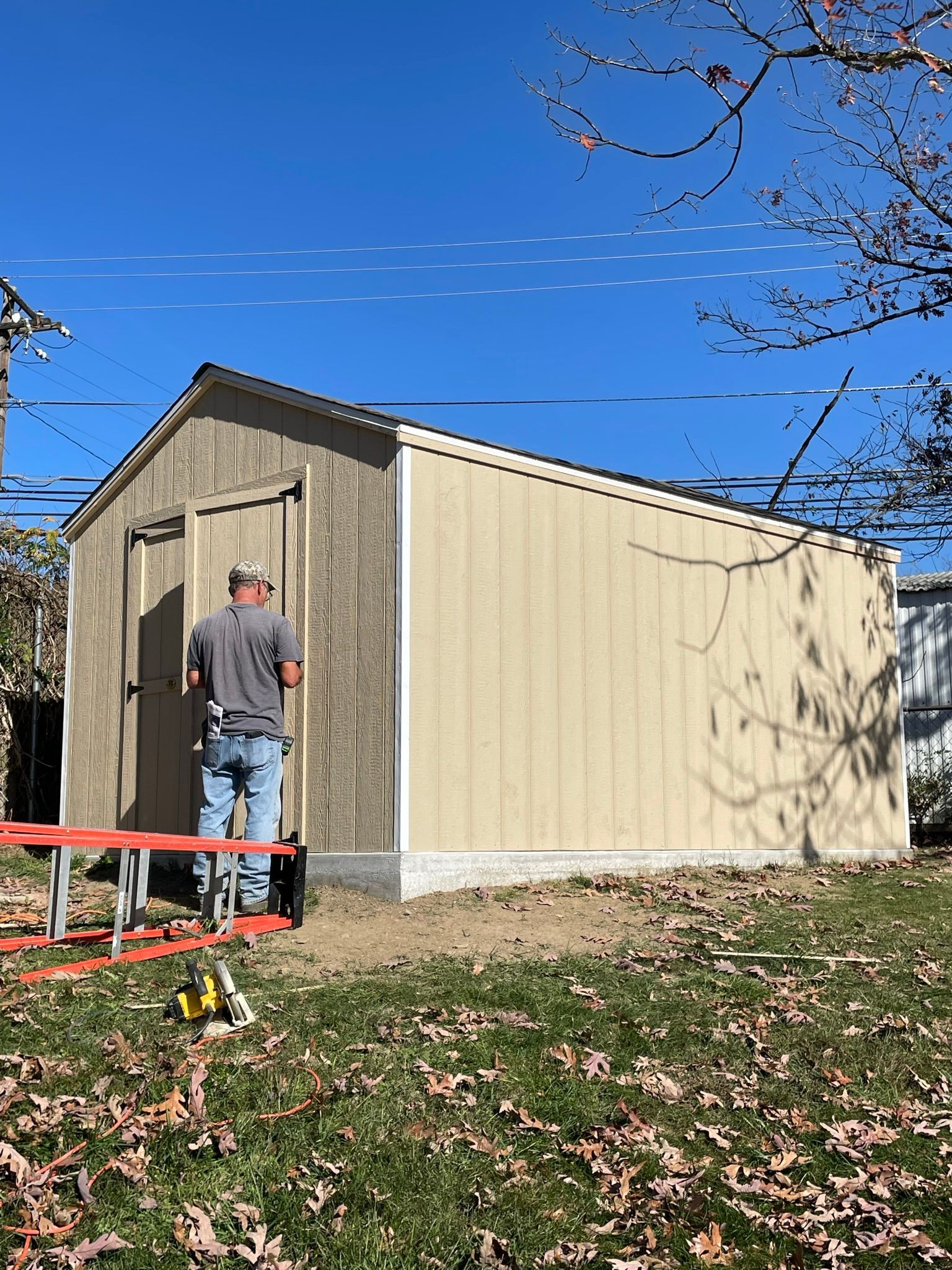 A man is standing in front of a shed.