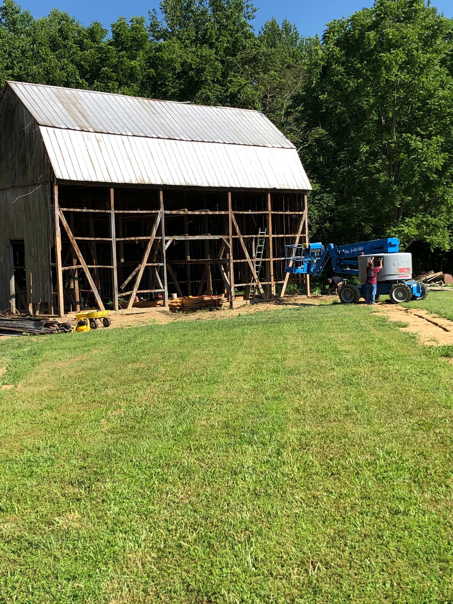 An old barn is being remodeled in a grassy field.