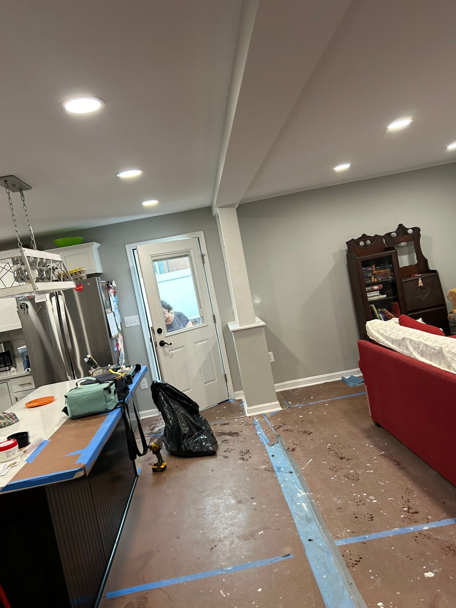 A living room with a red couch and a kitchen in the background.